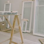 Interior of room with wooden workbench and windows removed from hinges with white frame placed near wall in light room during repair works